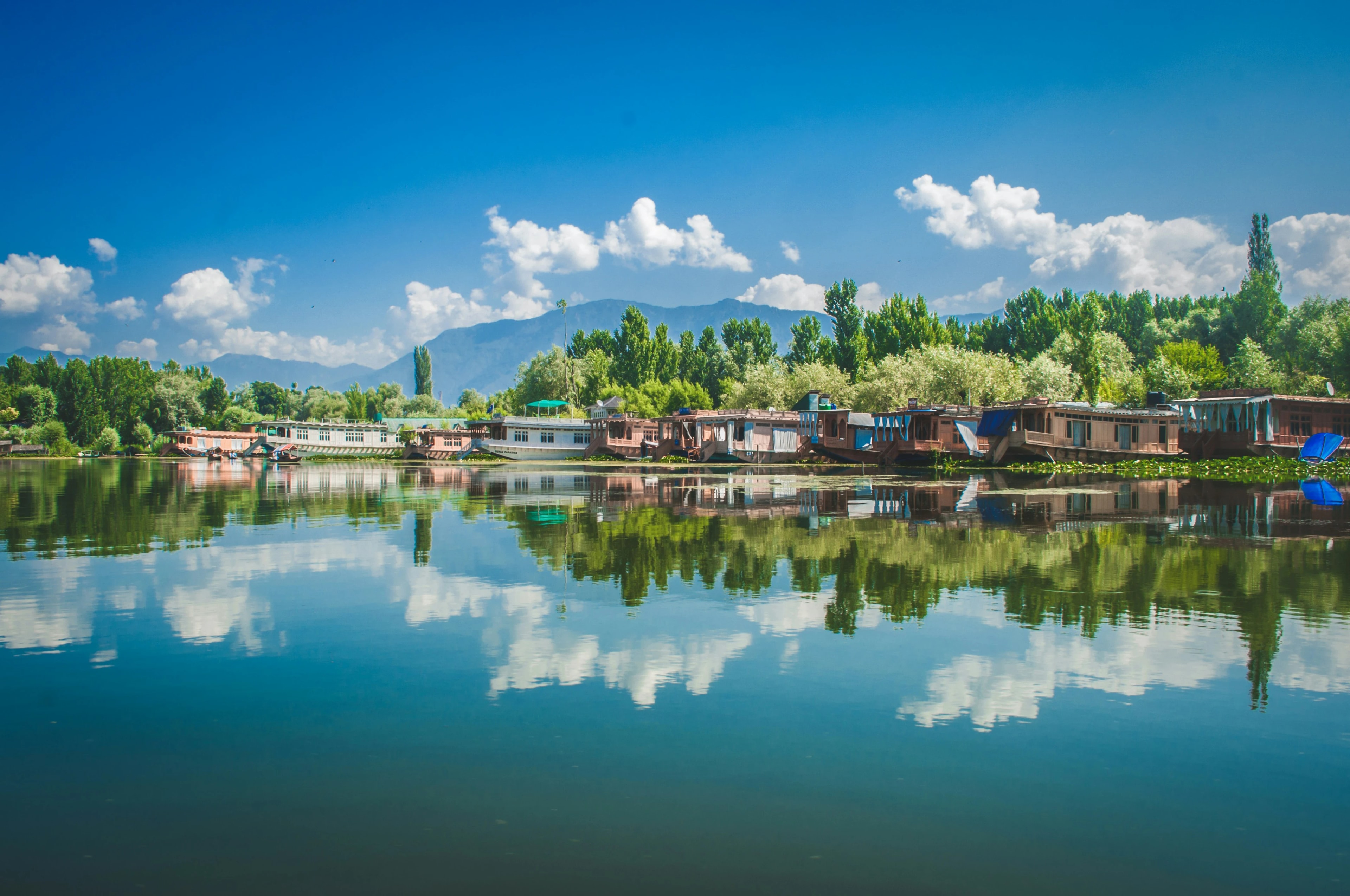 View of houseboats on Dal Lake with mountains in the background